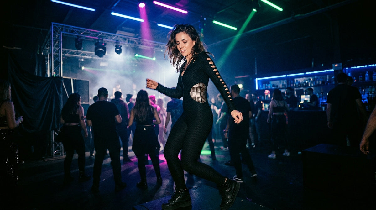 Frau im schwarzen Rave-Bodysuit im Club
