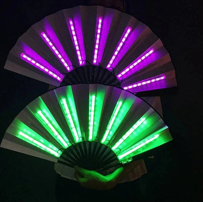 Zwei leuchtende LED Fächer in Pink und Grün in der Hand