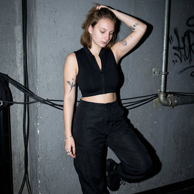 Schwarzes Rave Zip Top, Model lehnt an der Wand