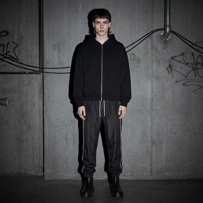 Model frontal in Reflective Nightflow Hose, schwarz, ideal für Techno-Events.